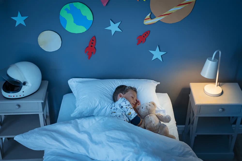 Little boy asleep in bed in a space-themed bedroom