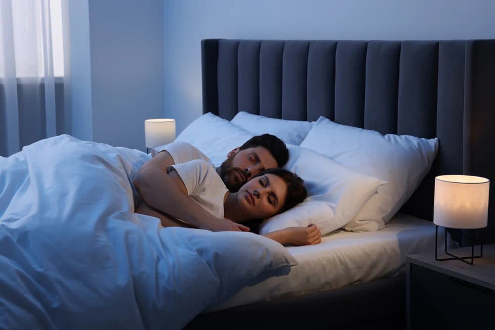 Couple asleep on their bed in a dark room
