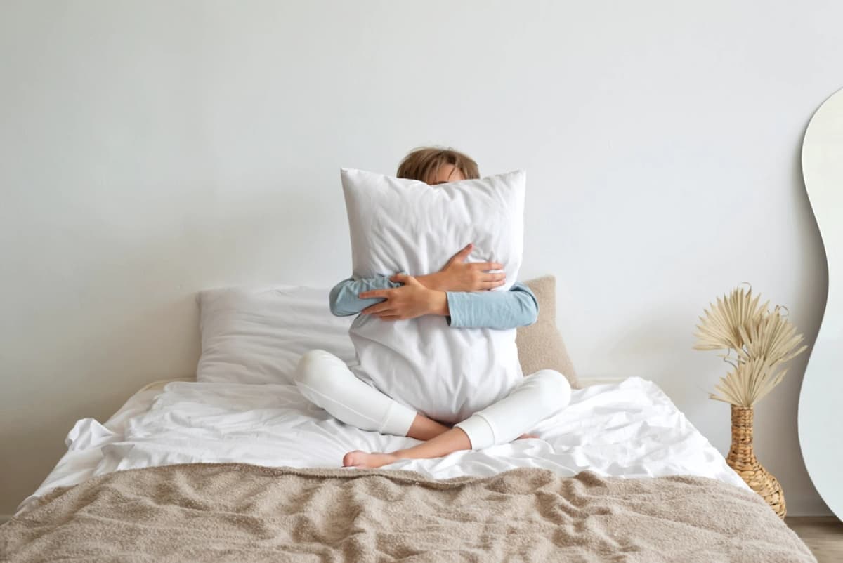 Woman on bed clutching a pillow
