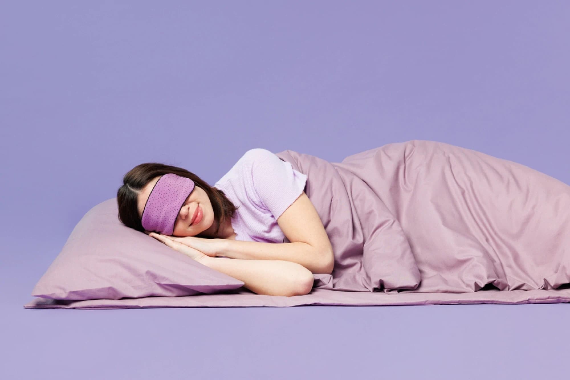 Young woman wearing purple pajamas asleep on purple sheets