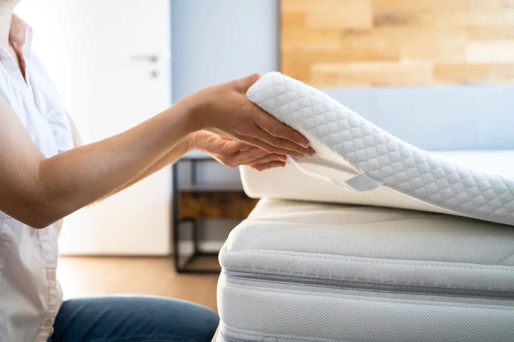 Mattress topper being laid on top of a mattress