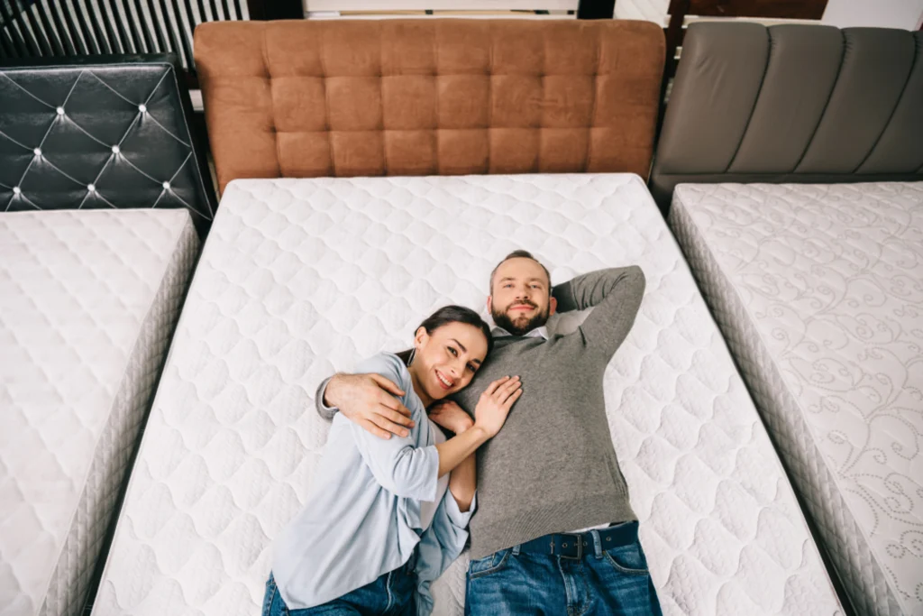 Man and woman lying on mattress in a store.