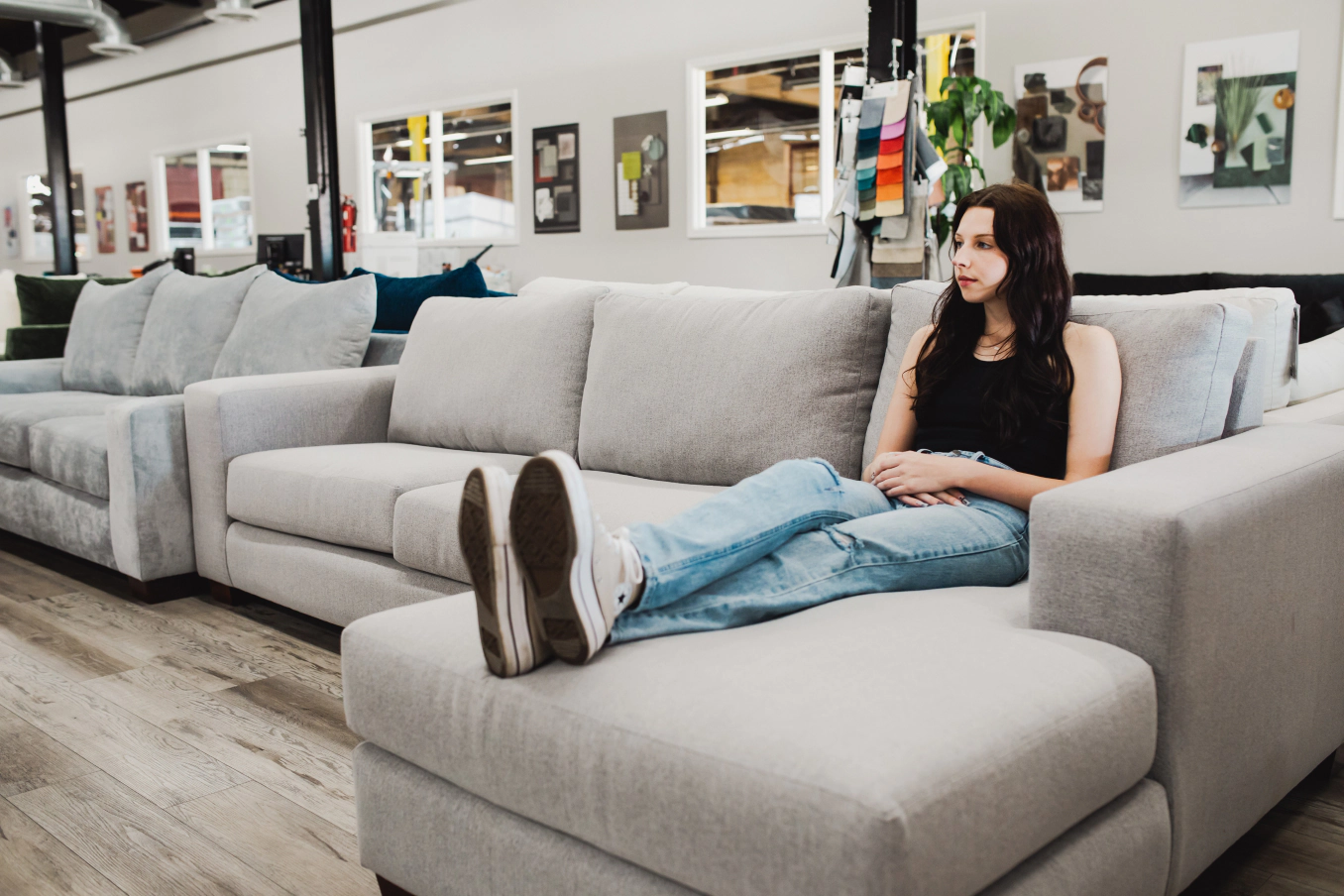 Young woman sitting on Living Designs Furniture sectional.